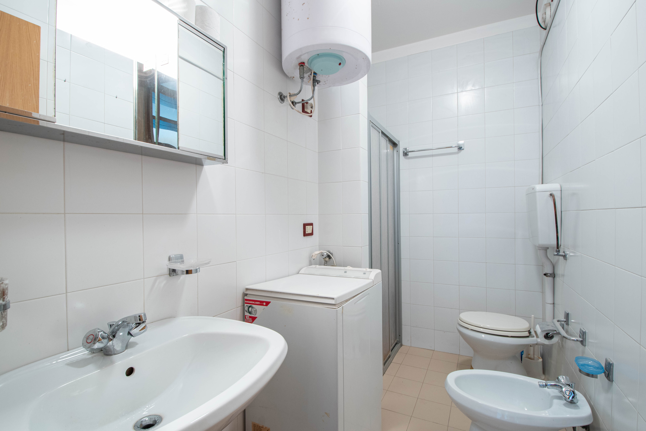 Bagno con box doccia e lavatrice dell'appartamento a Lignano Sabbiadoro