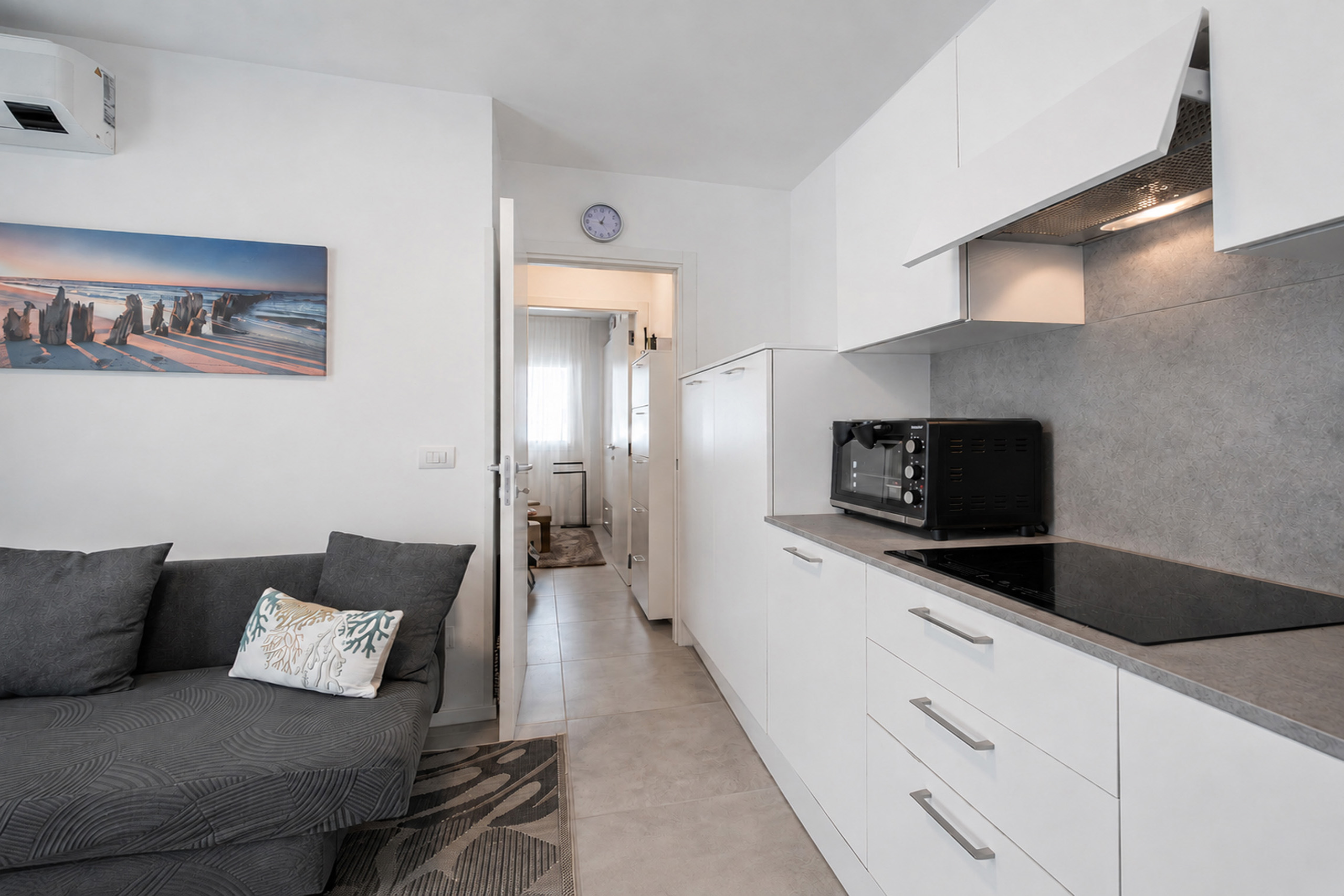 Soggiorno con divano, cucina a vista e passaggio verso la zona notte del bilocale MIRAMAR