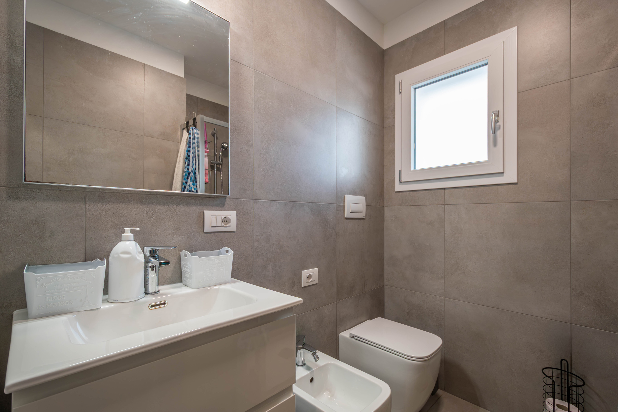 Bagno finestrato del bilocale MIRAMAR con mobile lavabo, specchio e sanitari