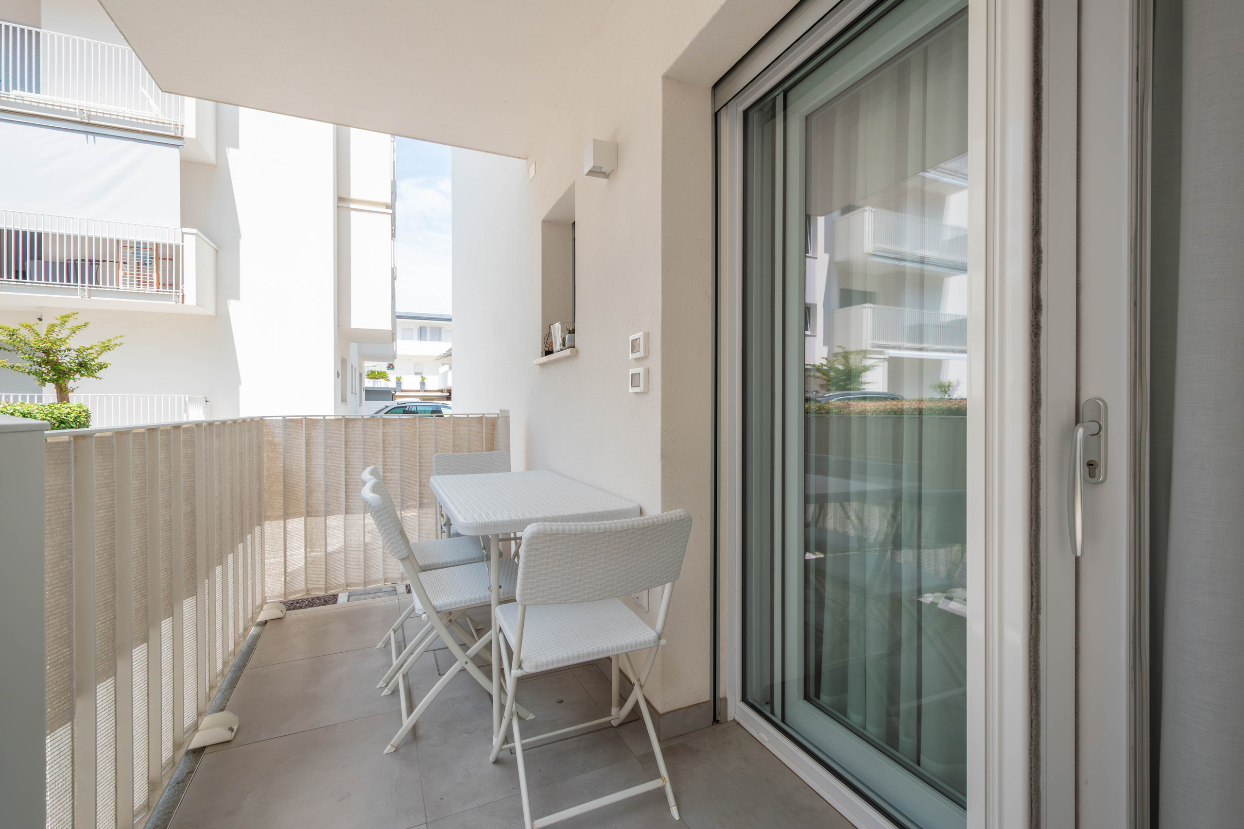 Patio coperto del bilocale MIRAMAR con tavolo e sedie davanti alla porta finestra